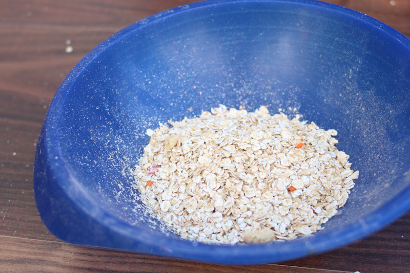 Putting the oat flakes from the dust container into a bowl after the suction test on a hardwood floor